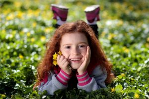 Petite fille rousse souriante dans l'herbe