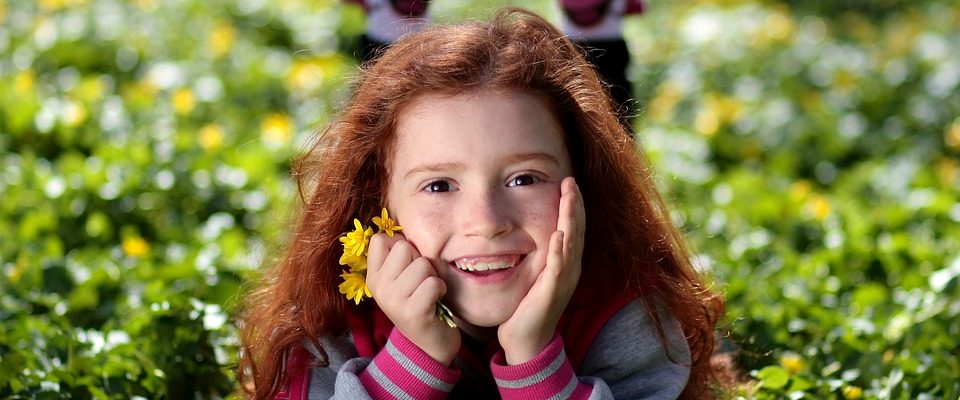 Petite fille rousse souriante dans l'herbe