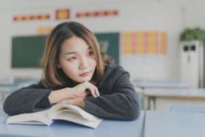 Jeune femme appuyée contre un livre ouvert avec un air pensif