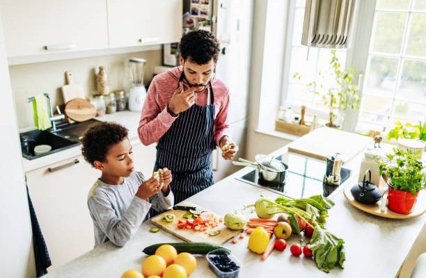 Père qui cuisine une salade de fruits avec son fils