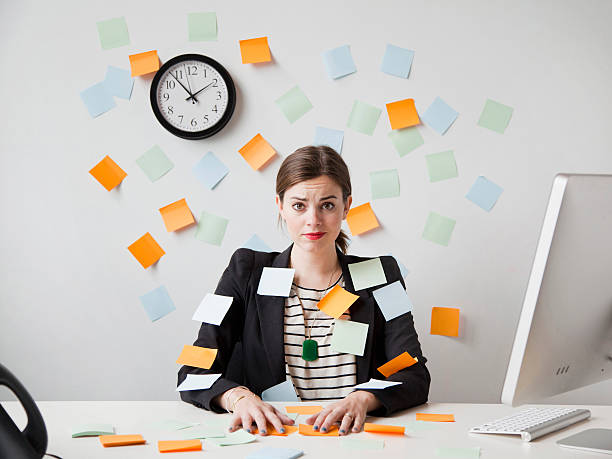 Jeune femme recouverte de post-it, assise à un bureau