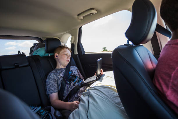 Petit garçon qui regarde un film sur un lecteur DVD dans la voiture