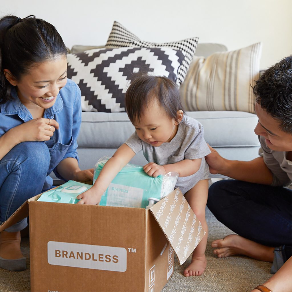 deux parents qui entourent leur bébé qui regarde le contenu d'un carton