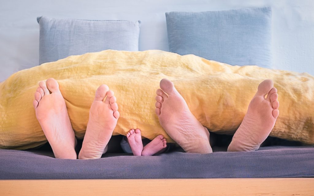 Couple au lit avec leur enfant en pyjamas