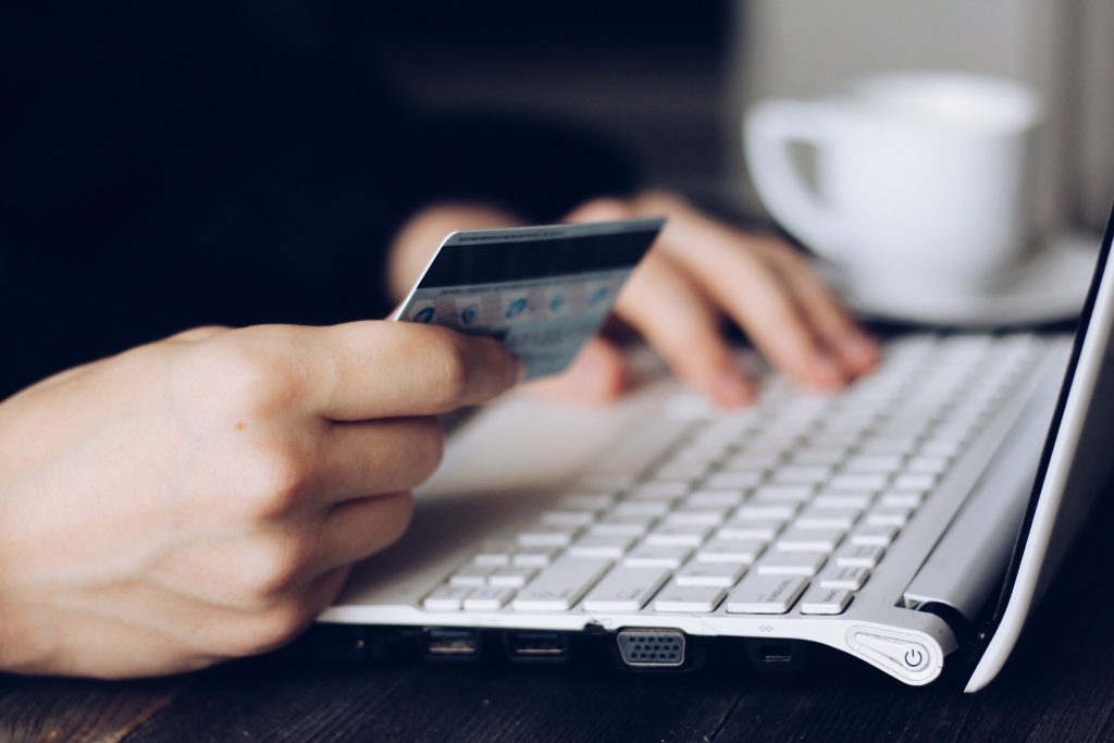 zoom sur les mains d'une personne tenant une carte de crédit près d'un clavier d'ordinateur et faisant du shopping en ligne